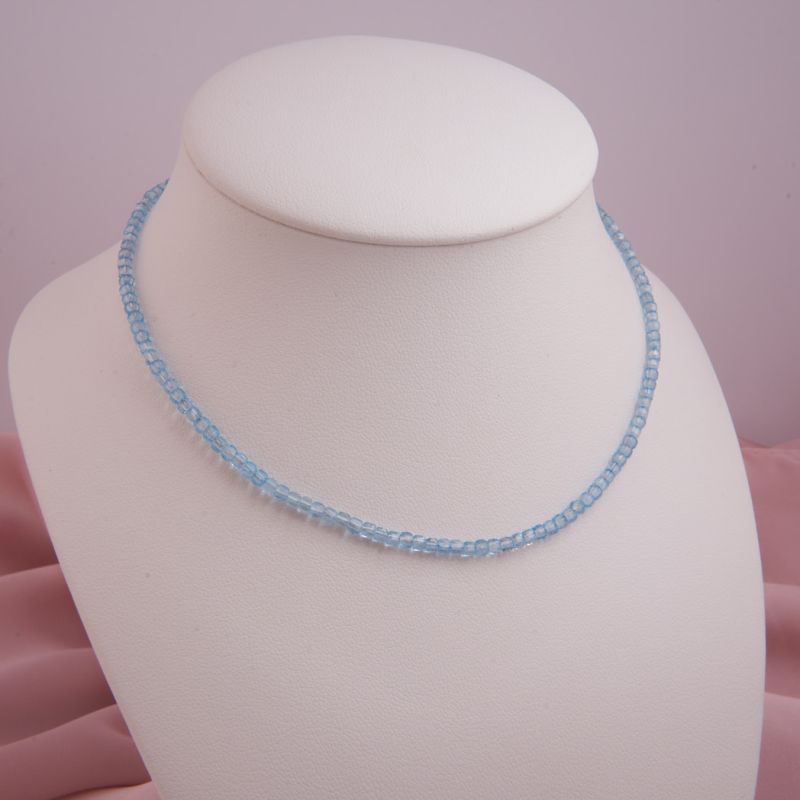 Preview: Zarte Damen-Halskette aus hellblauen, facettierten Blautopas-Würfeln mit silbernem Karabinerverschluss auf einer Schmuckbüste präsentiert.